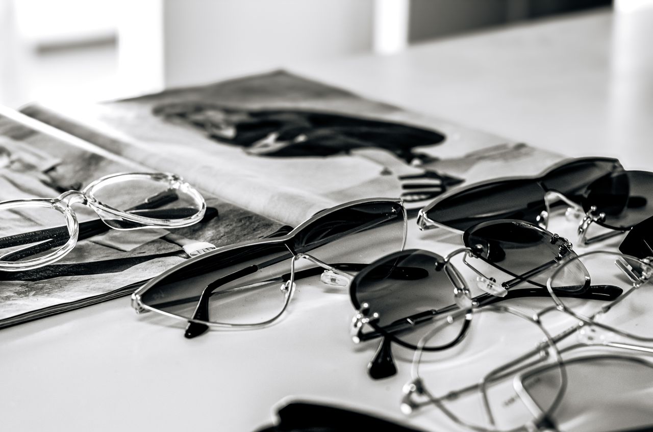 hero-img-02 Stylish sunglasses arranged on a glossy magazine in a sleek black and white composition.