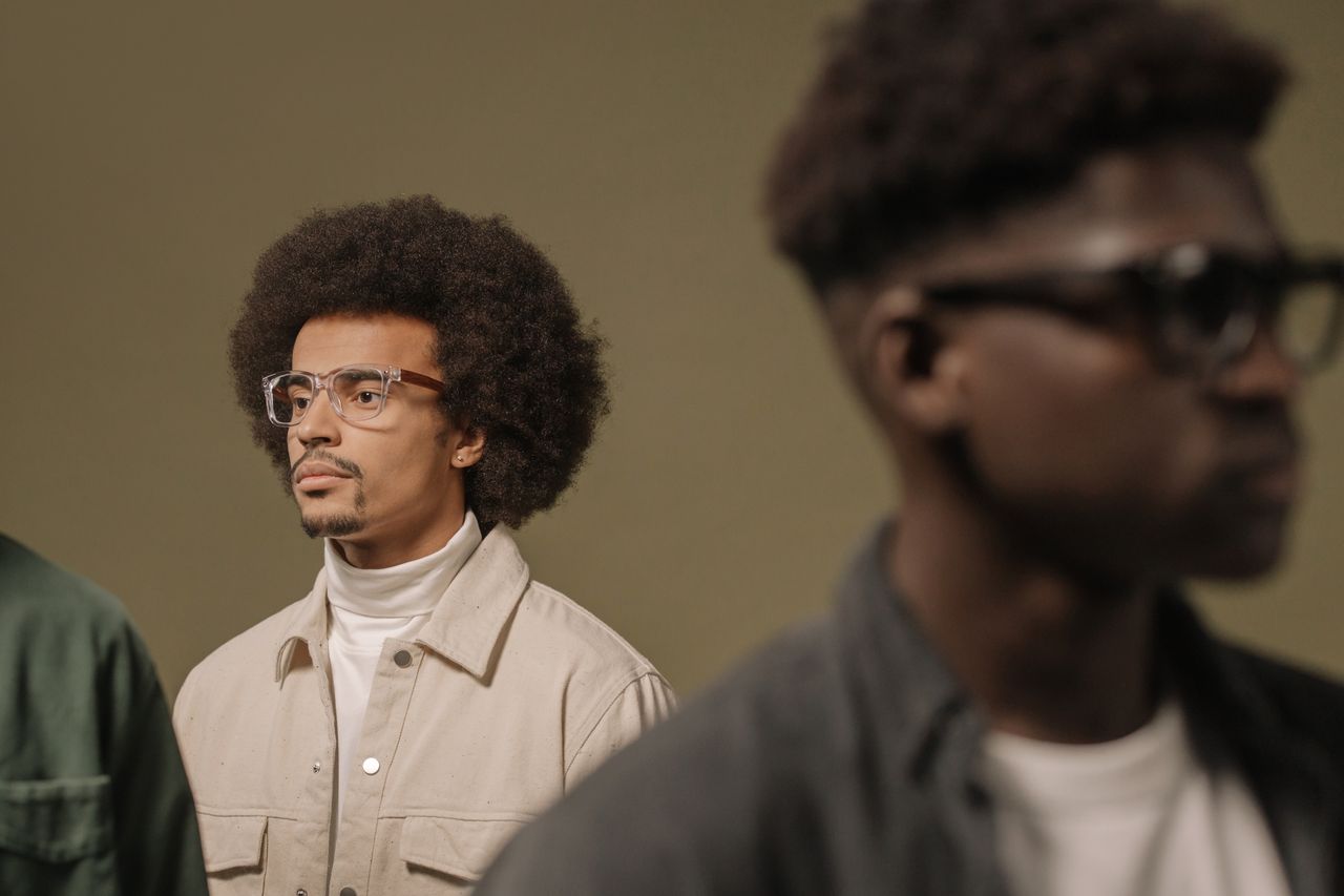 hero-img-01 Fashionable men with afro hairstyles and eyeglasses, portraying modern style and confidence.